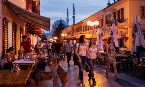 Pedestrianised street in the centre of Shkoder showing many people sat at cafe tables enjoying food and drink