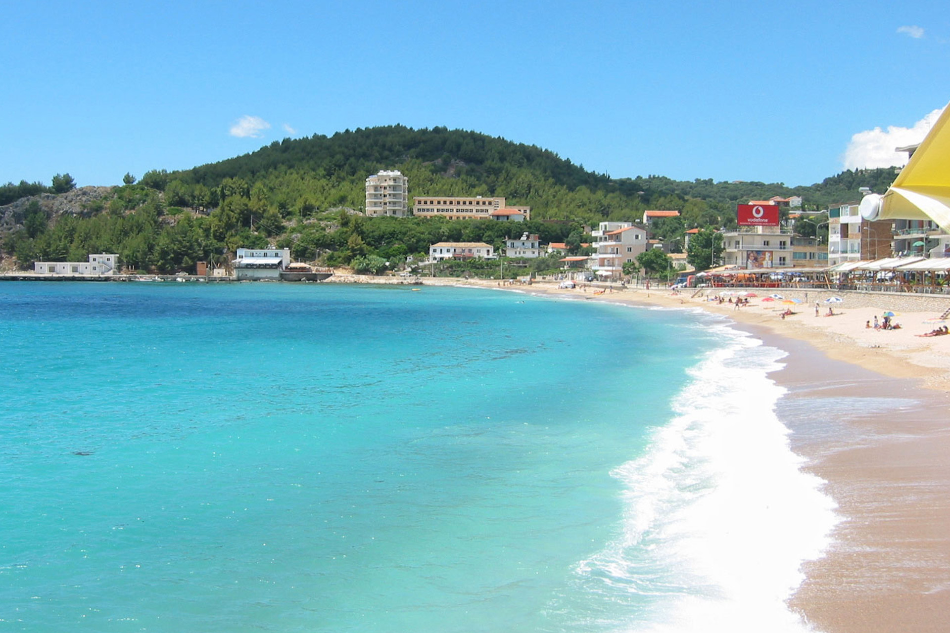 A view along Himare Beach on the Albanian Riviera with some people lying under their beach umbrellas