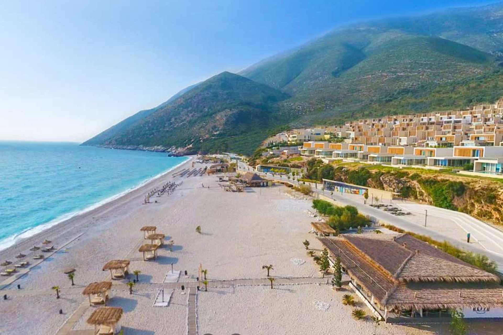 A view of Palase Beach on the Albanian Riviera with mountains rising in the background. YOu can also see a number of villas which are part of the Green Coast Resort development.