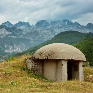 An image of one of the thousands of concrete Bunkers that surround Albania's countryside with the Albanian Alps in the background