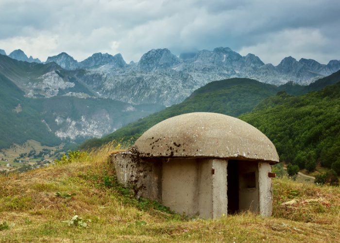An image of one of the thousands of concrete Bunkers that surround Albania's countryside with the Albanian Alps in the background